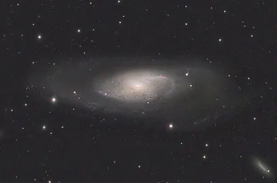 Faint spiral galaxy with nearby stars and a smaller galaxy