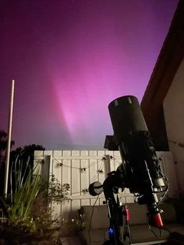Telescope setup under a glowing night sky